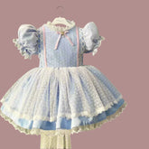 Children's blue polka dot dress with lace details on a hanger.