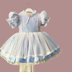 Children's blue polka dot dress with lace details on a hanger.

